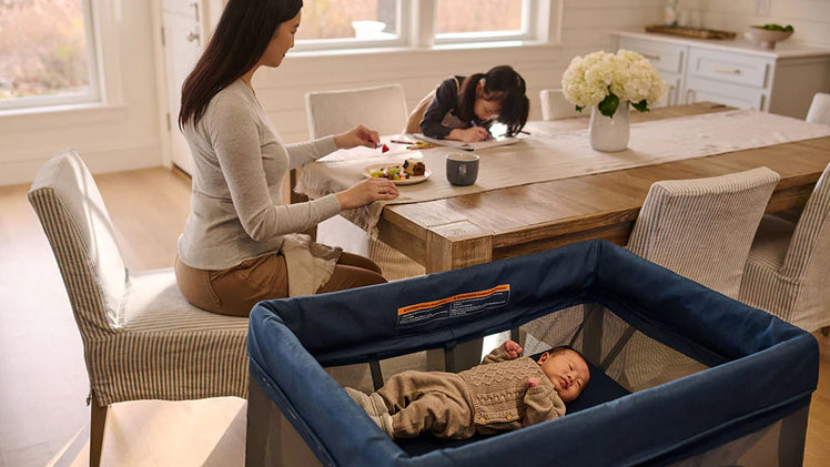 Mom And Preschooler Sitting at Dining Room Table with Baby in UPPAbaby REMI Portable Playard
