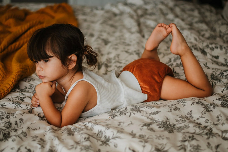 Little Girl Lounging on Bed with Cloth Diaper