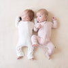 Babies snuggling in their zipper rompers in the shades blush and cloud.