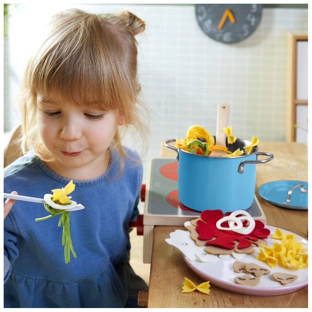 A young child playing pretend with an adorable pasta set.