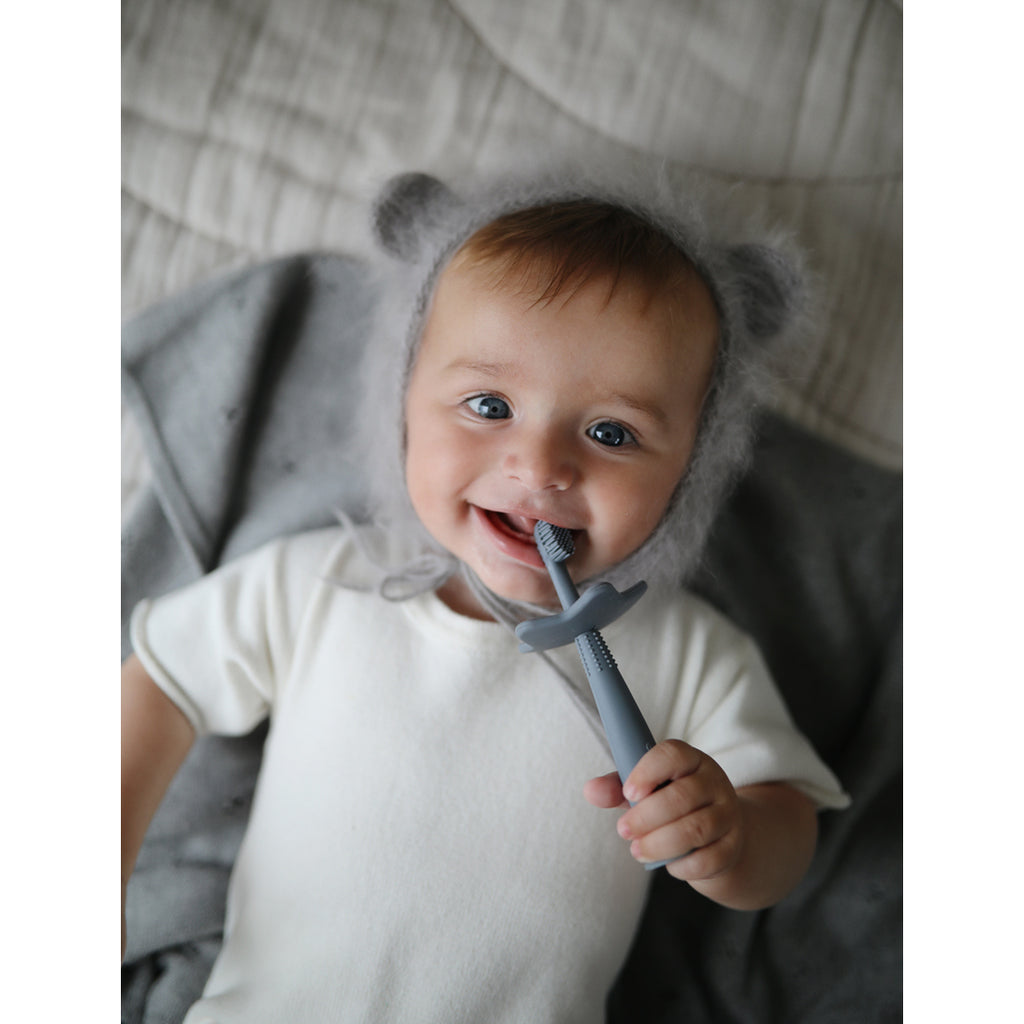Baby using adorable training star toothbrush in the color tradewinds.