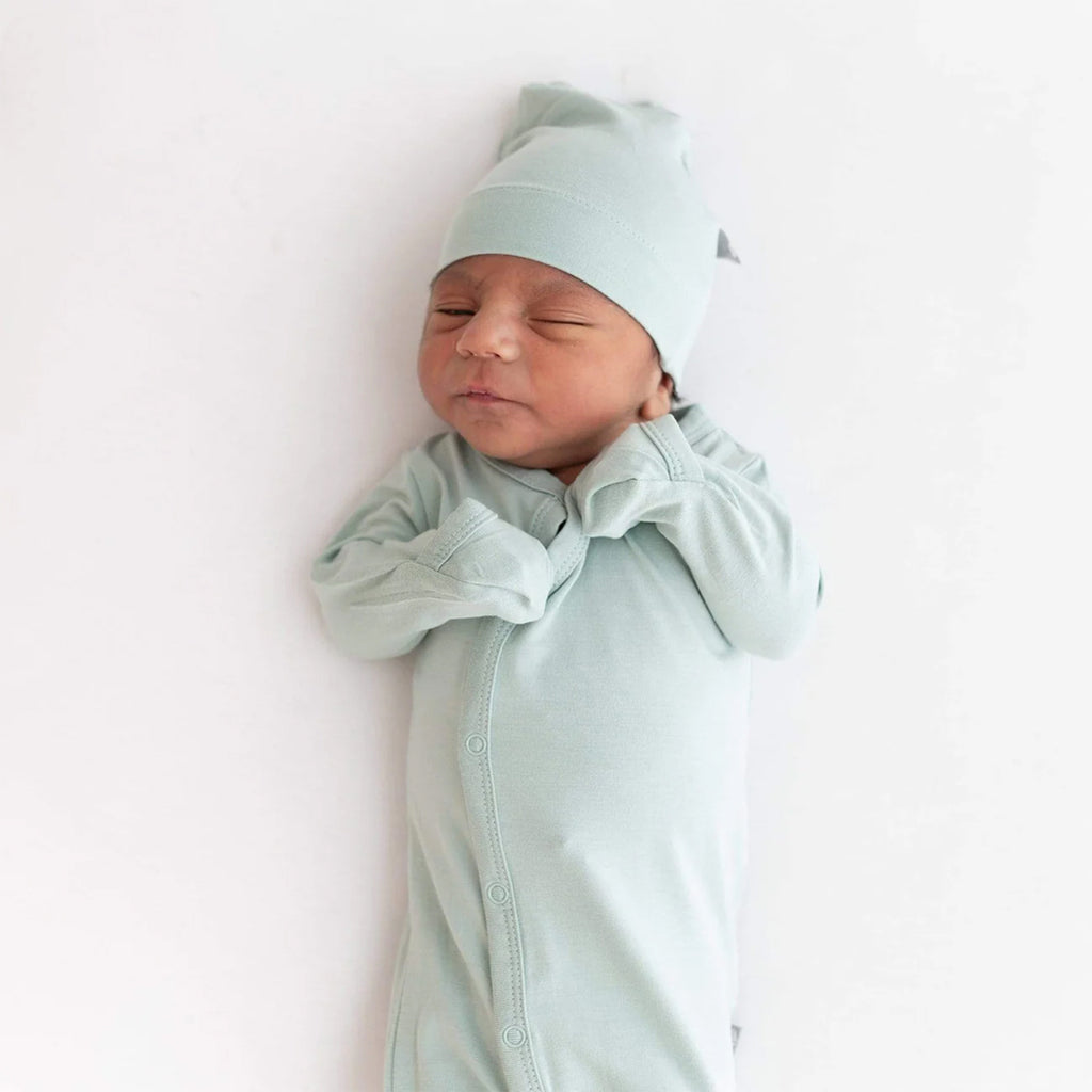 newborn in bundler and wearing Kyte sage baby hats  