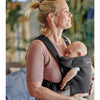 mother smiling facing sideways with infant in babybjorn mini baby carrier
