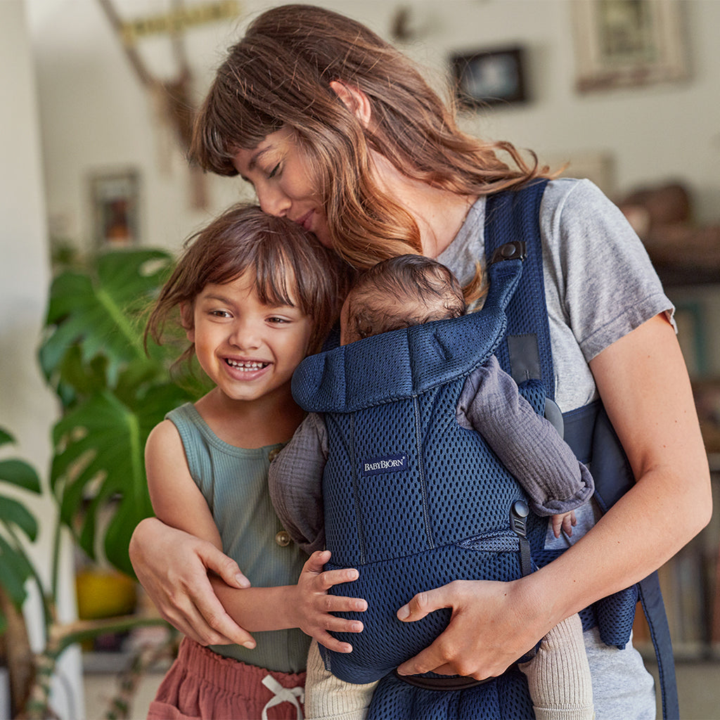 mom with daughter and carrying another child in best baby carrier by babybjorn