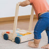 Plan Toys Baby Walker Infant Toddler Push Toy & Blocks Set - A cild is pushing the walker around their home 