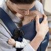 mom attending to infant in navy blue mesh baby bjorn mini carrier