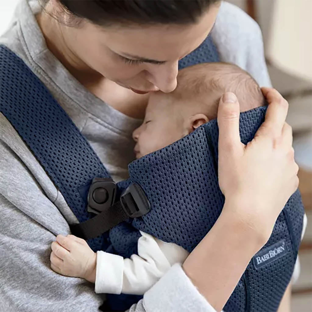 mom attending to infant in navy blue mesh baby bjorn mini carrier