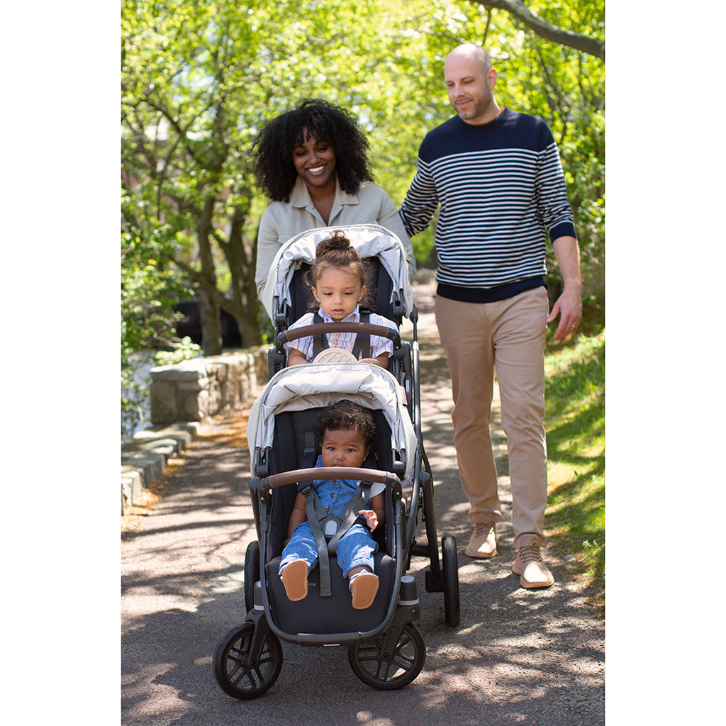 Parents walking with Uppababy double stroller in grey