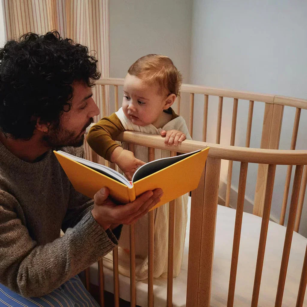 father reading book for child in sustainable crib