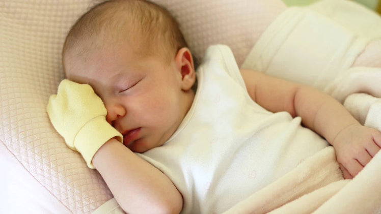 Sleeping Baby Wearing Yellow Protective Mittens