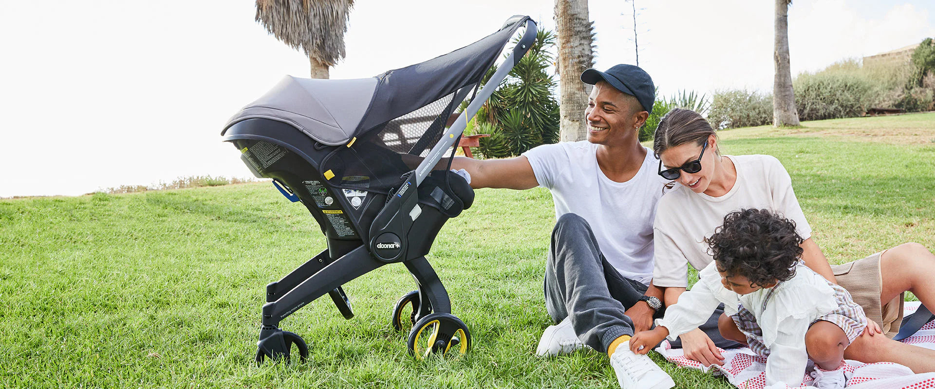 Family Playing in a Park with Baby in a Car Seat with Shade Canopy