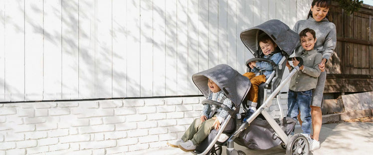 Mom Pushing Children in UPPAbaby VISTA Stroller with Two RumbleSeats and Sibling Piggyback Attachment 
