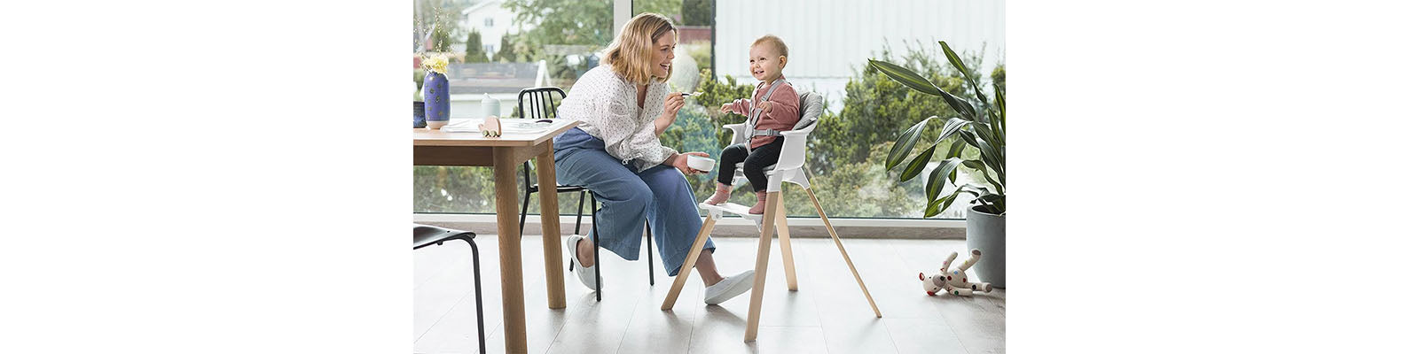 Woman Feeding Baby in Highchair with Spoon and Bowl