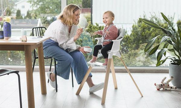 Mother Using Silicone Baby Spoon to Feed Child in High Chair