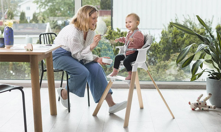 Mother Using Silicone Baby Spoon to Feed Child in High Chair