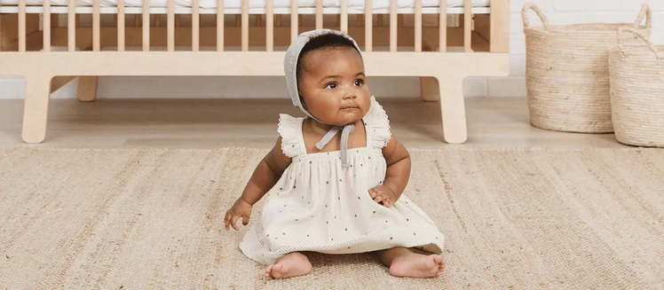 Baby Wearing Quincy Mae Dress and Bonnet in Nursery