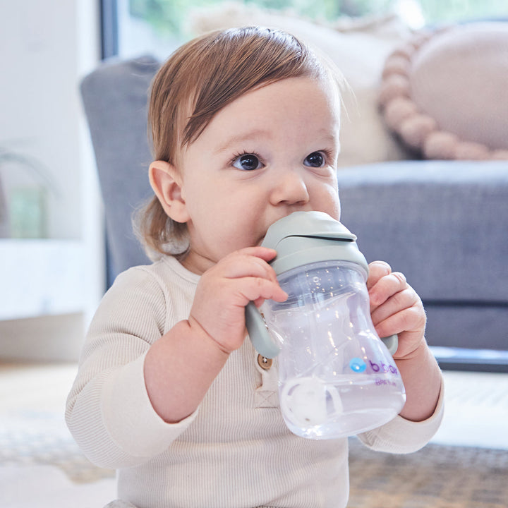 baby in living room drinking from blue no spill sippy cup by b.box