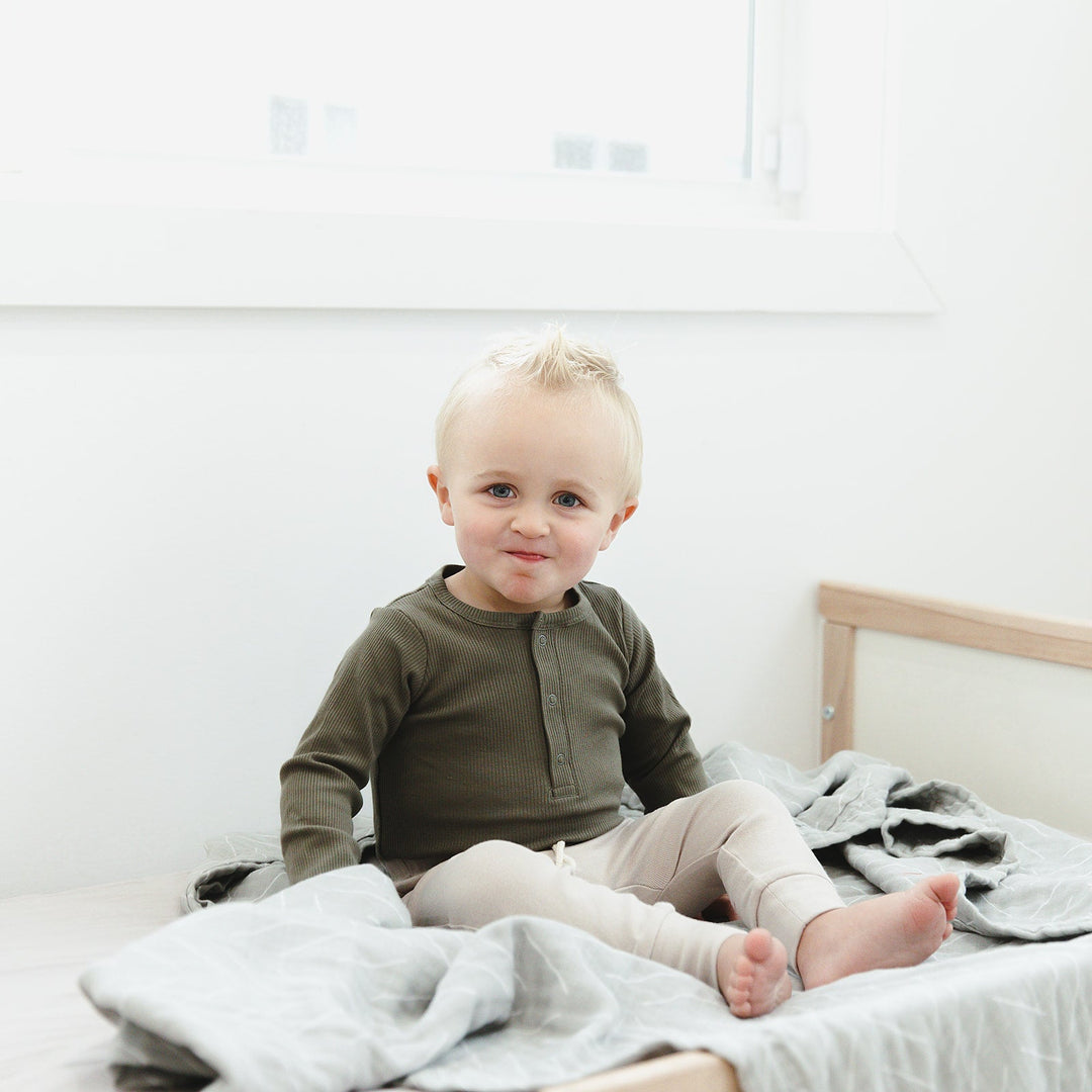 Baby modeling the Mebie Baby Winter Green Organic Snap Long Sleeve Ribbed Bodysuit, a soft ribbed baby bodysuit for everyday