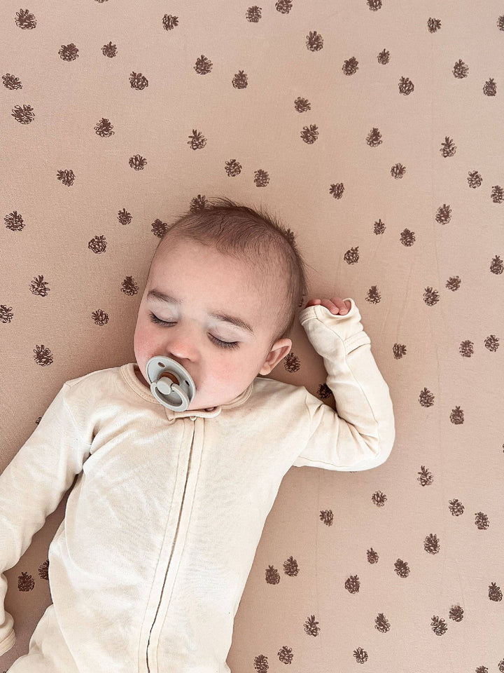close up of baby peacefully sleeping on extra soft non toxic loved baby pinecone oatmeal crib sheets 