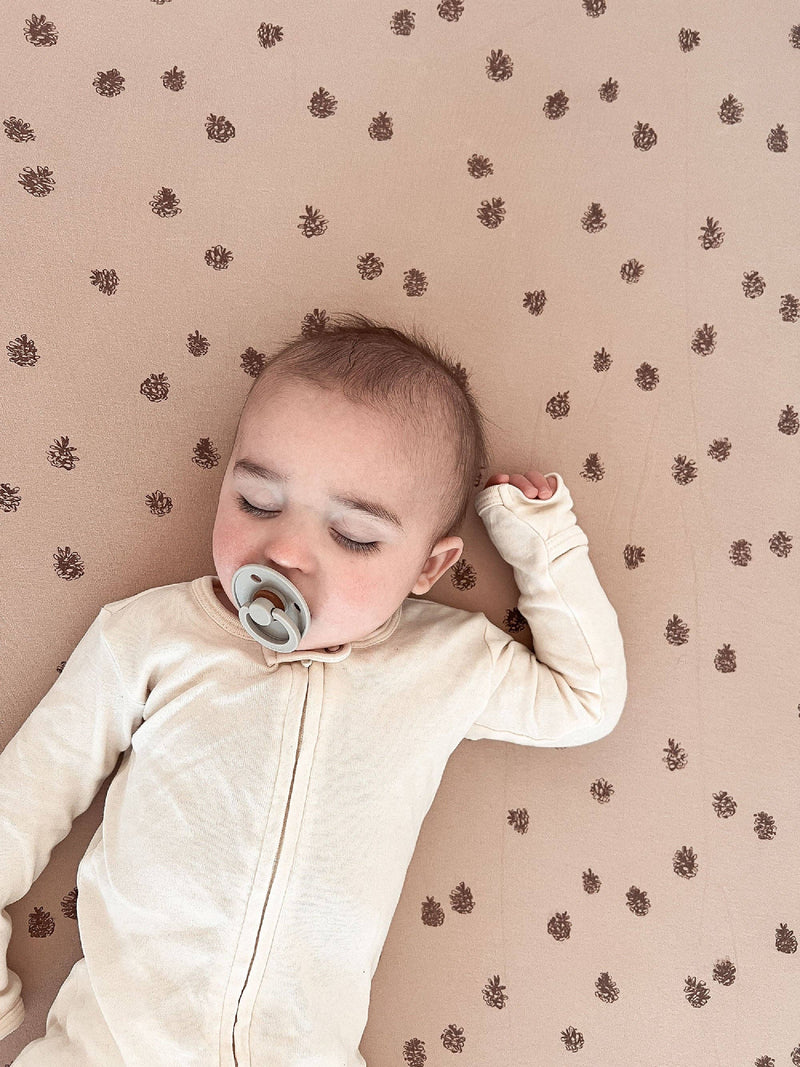 close up of baby peacefully sleeping on extra soft non toxic loved baby pinecone oatmeal crib sheets 