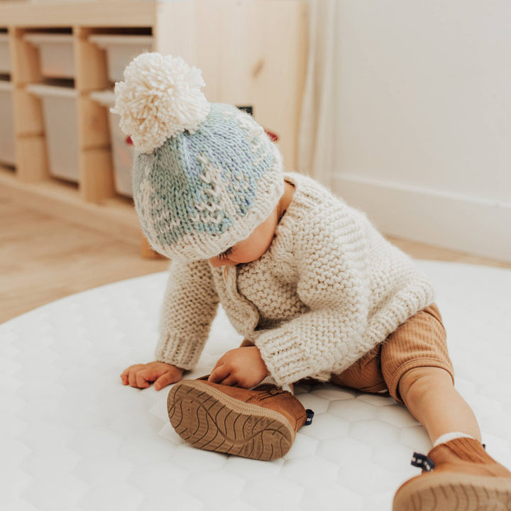 baby in garter stitch cardigan and winter forest blue hand knit huggaluggs beanie 