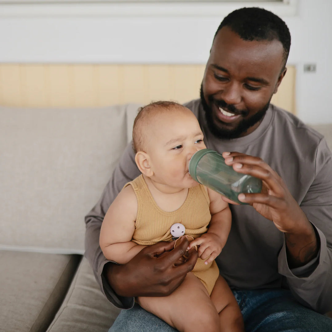 Lifestyle photo of Mushie Soft Spout Sippy Cup Dried Thyme - toddler drinking from spill-resistant training cup