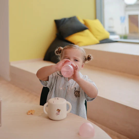 Young child drinking from Mushie Soft Spout Sippy Cup at library - BPA-free toddler training cup in use