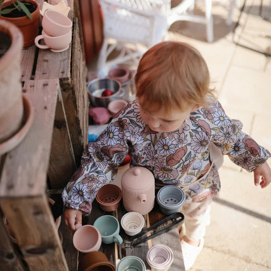 baby playing with collection of mushie cups and saucers for child