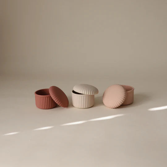 Mushie pink silicone baby food containers flat lay - three reusable snack containers on minimal background