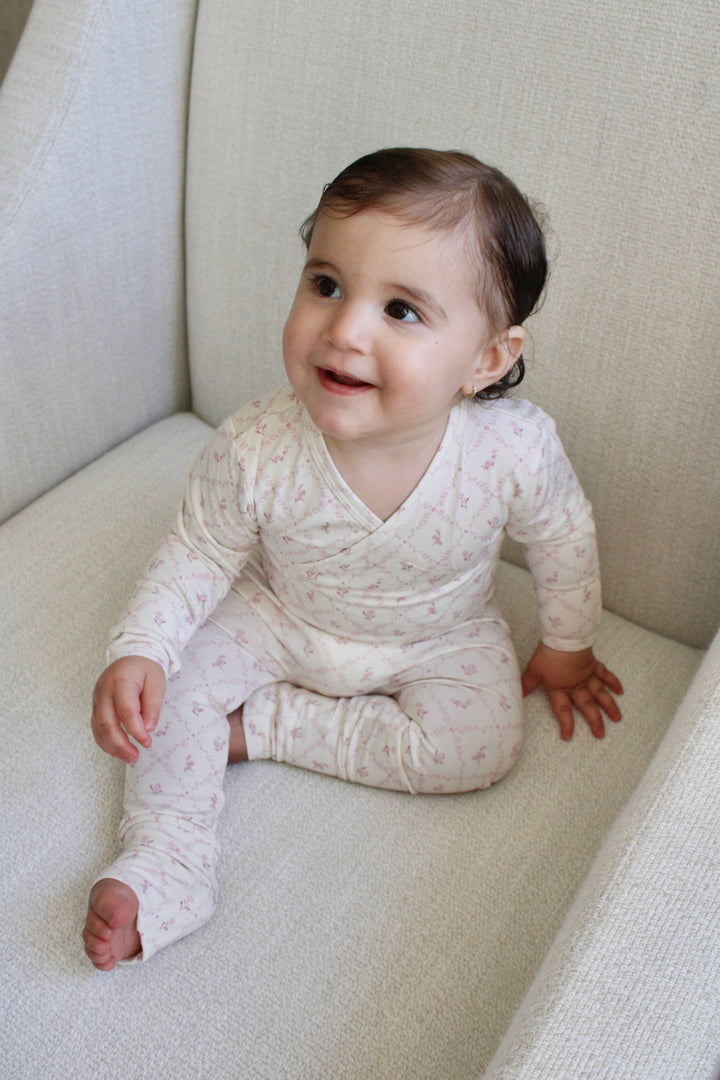 Baby wearing Little Threads mauve lattice bamboo footie in crib, cozy infant sleepwear for sensitive skin and soft bamboo baby pajamas
