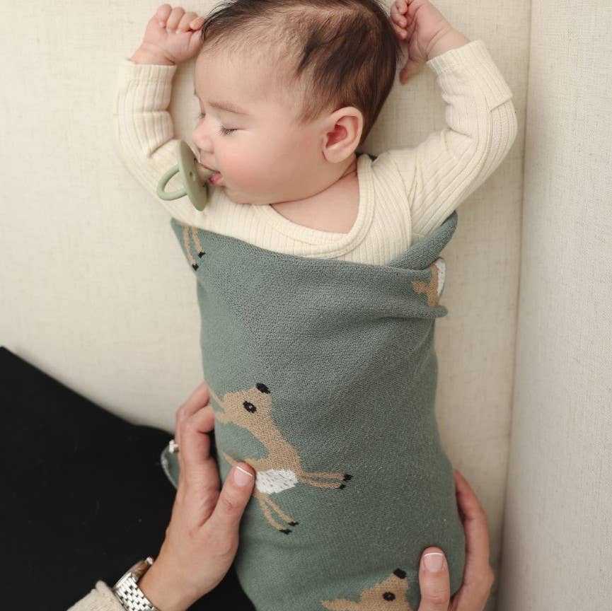 baby wrapped in blue la la sage green deer patterned swaddle blanket 