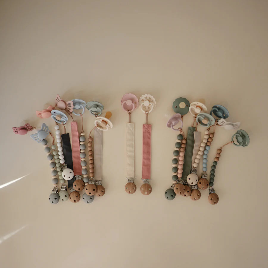 The Mushie Linen Pacifier Clip adds charm while keeping baby pacifiers within reach.