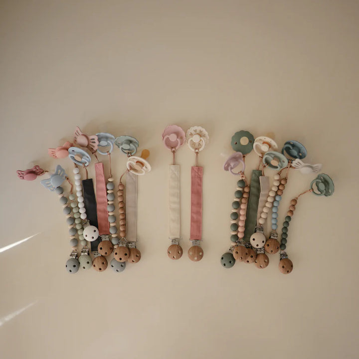 The Mushie Linen Pacifier Clip adds charm while keeping baby pacifiers within reach.