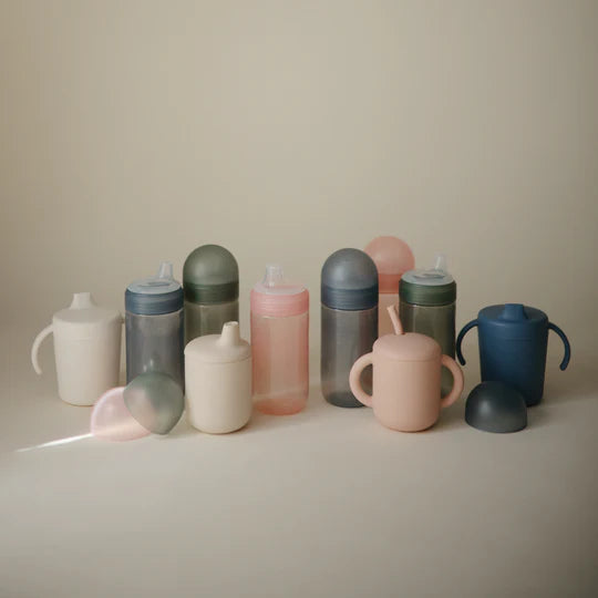 Mushie Soft Spout Sippy Cup flat lay styled - BPA-free toddler sippy cup with coordinating baby accessories