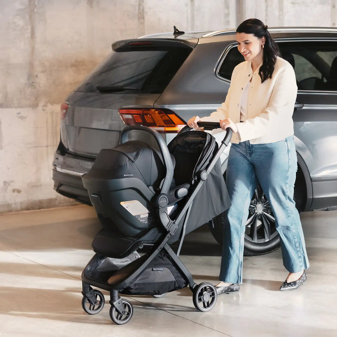 woman walking in garage with minu v3 and mesa v3 car seat away from car