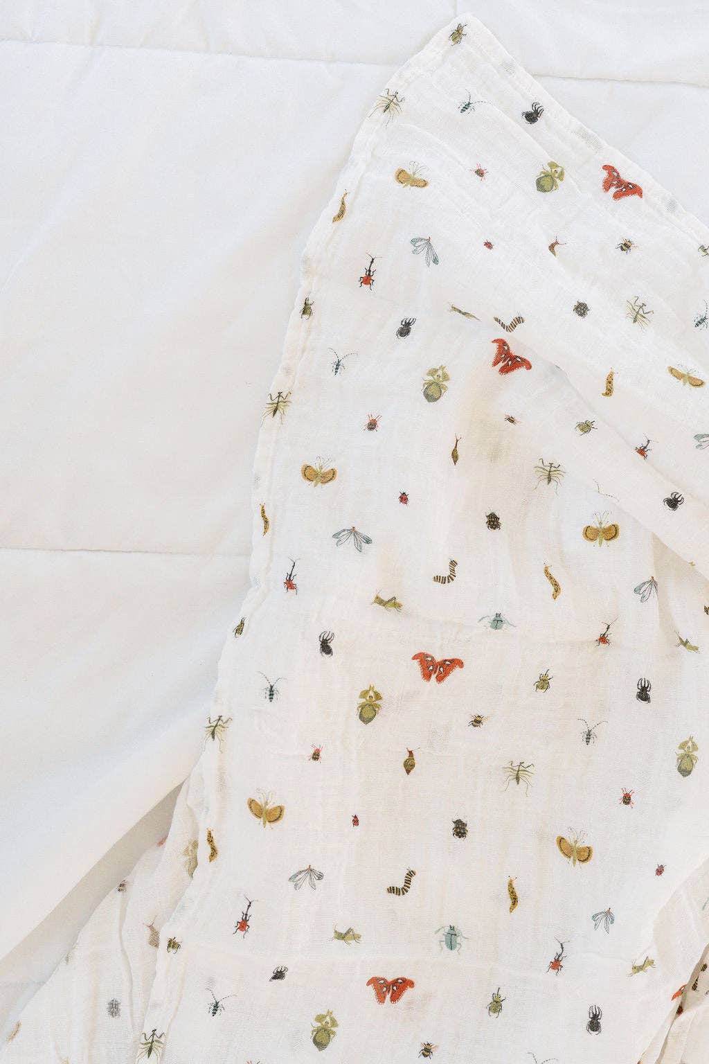 Soft, playful, and cozy, the Cutie Crawlies Swaddle by Clementine Kids is a perfect baby swaddle in muslin.