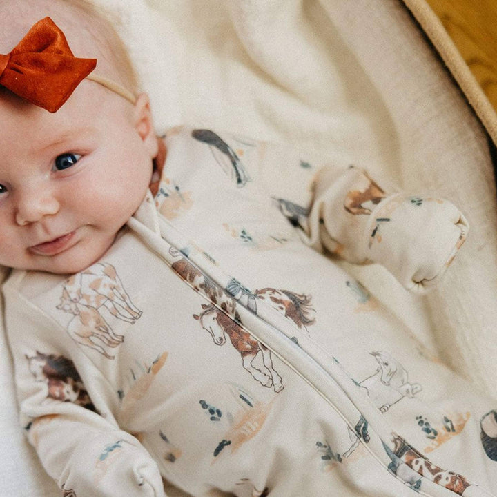 Baby wearing Copper Pearl Montana footie pajamas close up, soft bamboo baby sleepwear for sensitive skin and comfortable movement