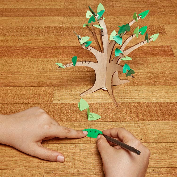 Child adding a leaf to Gratitude Tree children's activity