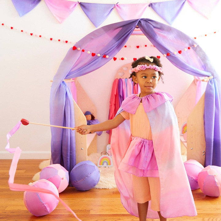 Streamer in hand, a child dives into imaginative play wearing the Sarah's Silks Blossom Cape