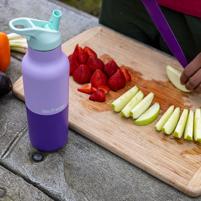 Klean Kanteen Rise Classic 16oz Bottle in Orchid Kaleidoscope on a lunch table, featuring non toxic stainless steel construction.