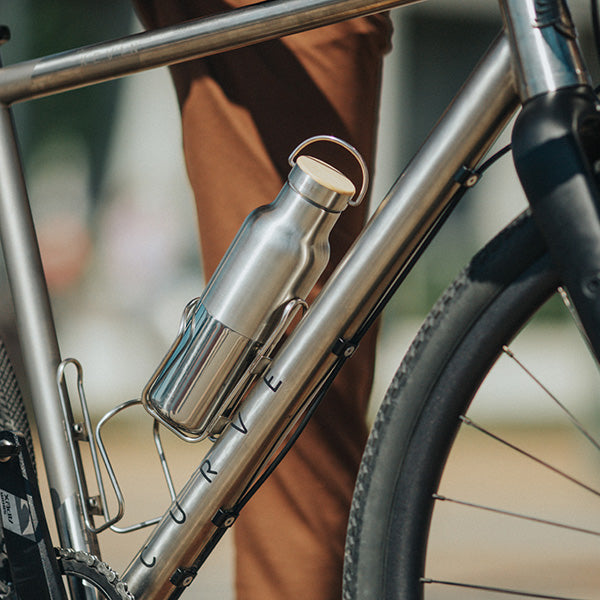Klean Kanteen Rise Reflect 16oz Silver Water Bottle shown in a bike cage, emphasizing its leak proof stainless steel construction.