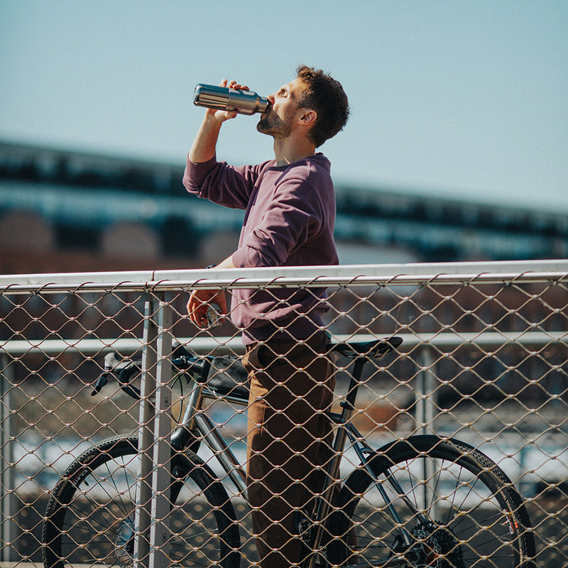 Man cycling with Klean Kanteen Rise Reflect 16oz Silver Bottle, designed for no leak performance and sustainable adventure.