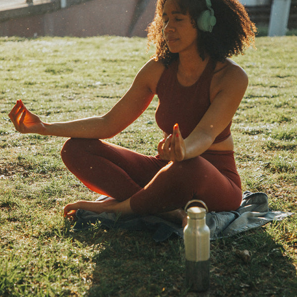 Outdoor yoga scene with Klean Kanteen 16oz Rise Reflect Bottle, made from bamboo and natural materials for hydrating with style.