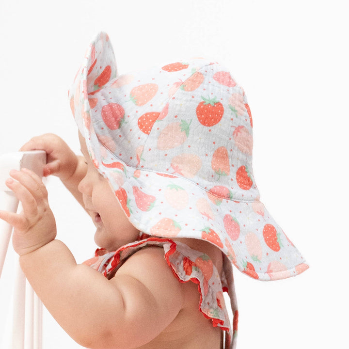 baby girl wearing strawberry patterned wide brimmed infant sun hat 