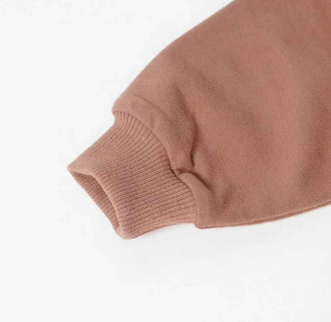 close up of cuff of sweater bebe boho bubble romper in pinkish red