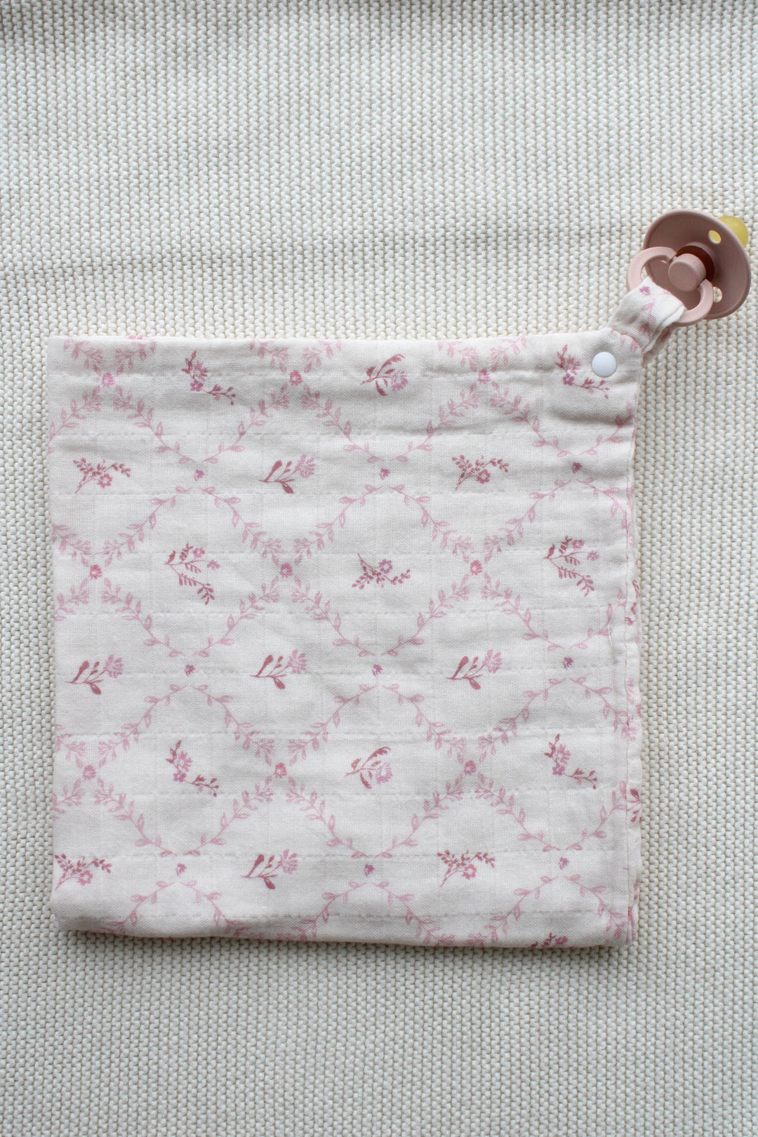 Little Threads baby lovey folded flat showing mauve lattice print and clip attachment