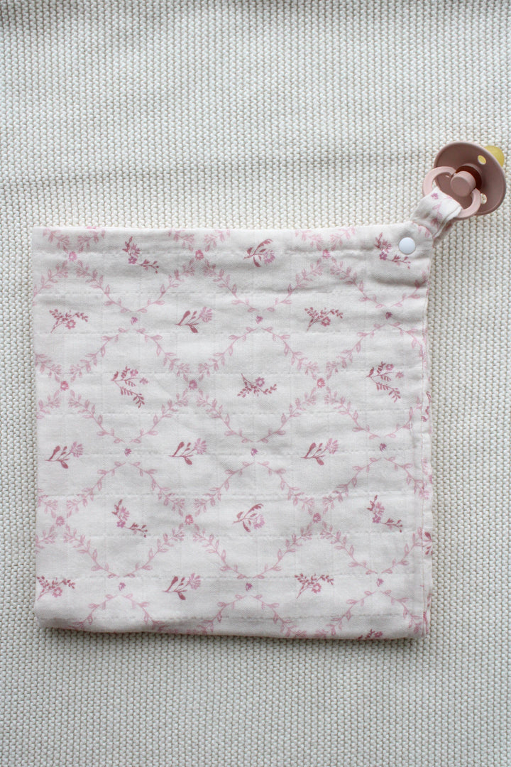 Little Threads baby lovey folded flat showing mauve lattice print and clip attachment