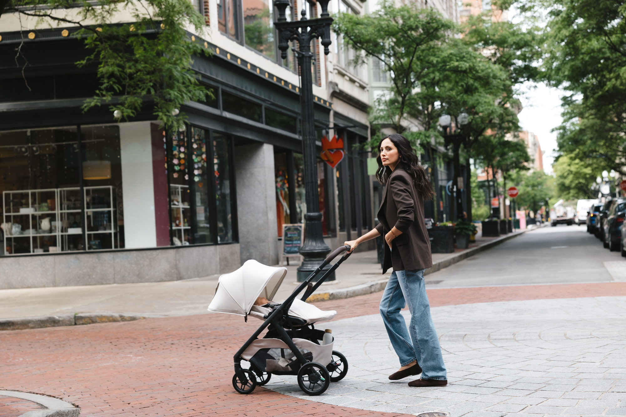 mother pushes uppababy kona stroller on busy city street 