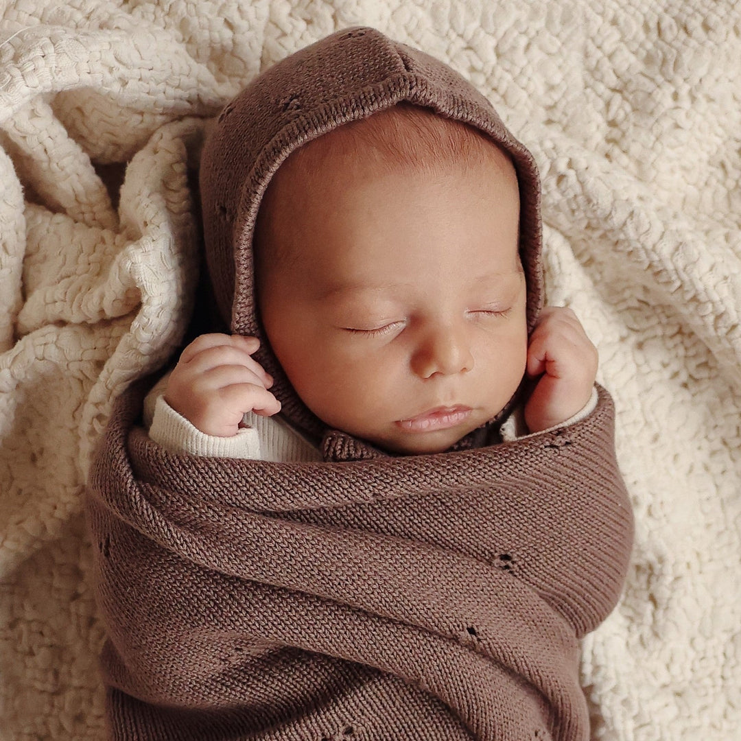 Newborn swaddled in Bleu La La Organic Pointelle Swaddle Blanket in mocha brown with matching hat for breathable newborn comfort.
