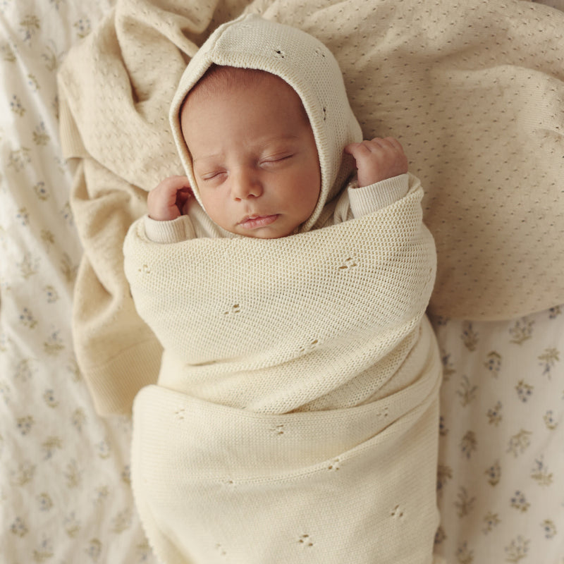 Newborn swaddled in Bleu La La Organic Pointelle Swaddle Blanket in butter cream for gentle breathable organic cotton comfort.